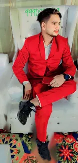 Man in a red suit seated on a white chair for mobile wallpaper.