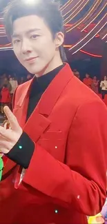 Person in a stylish red suit with peace gesture, in a vibrant setting.