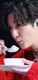 Person in a red sweater eating with a spoon.