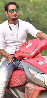 Young man riding a red scooter in stylish attire.