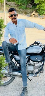 A stylish man sits on a motorcycle in an outdoor setting.