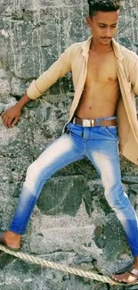 Young man balancing on a rope with a stone background.