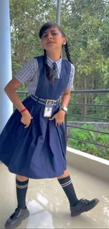 Student in school uniform posing outdoors with a green nature backdrop.