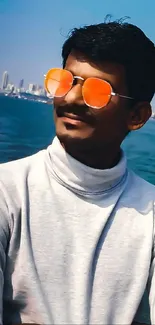 Person with orange sunglasses by the sea.