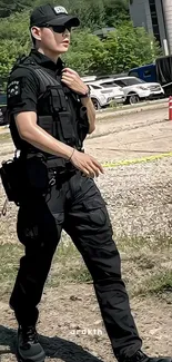 Person in tactical black uniform walking outdoors in an urban environment.