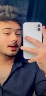 Young man taking a selfie with a smartphone in a stylish pose.