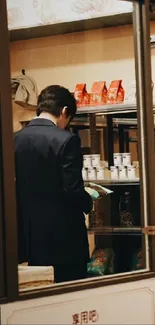 Man browsing in a stylish shop with shelves filled with a variety of products.