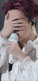 Singer with red hair, white shirt, holding microphone during performance.