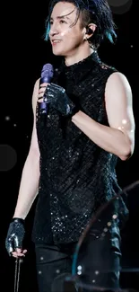 Singer in black outfit holding microphone on stage.