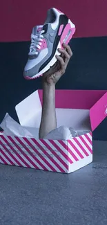 A sneaker emerging from a pink-striped shoebox.