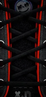 Black sneaker laces with red highlights on wallpaper.