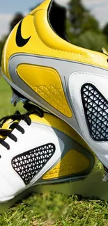 Yellow and white soccer cleats on a green grass field.