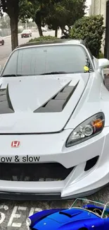 White Honda sports car with black hood accents.