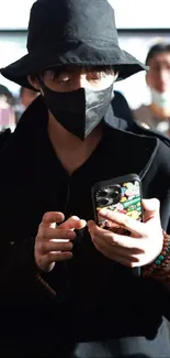 Person in black outfit, holding a patterned phone