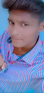 Young man in striped shirt against blue background.