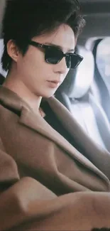 A stylish person wearing sunglasses in a brown coat.