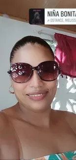 A smiling person wearing sunglasses indoors.