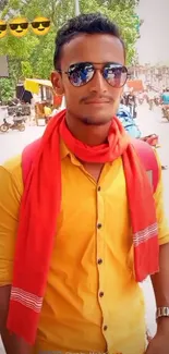 Fashionable guy with sunglasses, yellow shirt, and red scarf on a street.