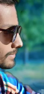 Profile of a stylish man wearing sunglasses outdoors.