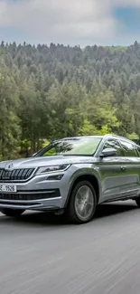 Sleek SUV driving through a lush forest setting on a clear day.