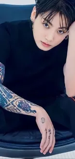 Tattooed individual in stylish pose, black t-shirt.