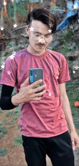 Man in a pink shirt using a smartphone outdoors.