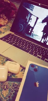 Sleek tech setup with laptop, iPhone, AirPods on patterned blanket.