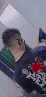 Back view of a person wearing an anime-themed T-shirt, holding a phone.