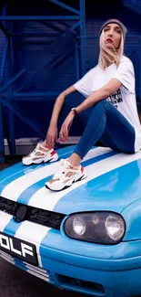 Person sitting on a blue sports car in urban setting.