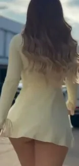 Woman in beige dress walking in city scene.