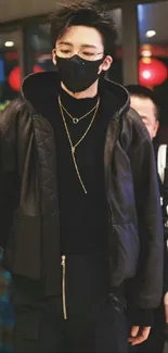 Person in stylish black outfit and gold necklaces, exuding urban fashion.