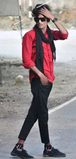 A stylish man in red and black stands on a road.