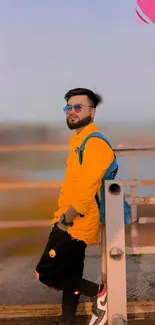 Man in yellow jacket leaning on railing, urban background.