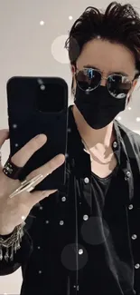 Fashionable person with sunglasses and black outfit taking a selfie.