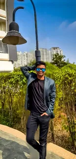 Young man standing outdoors in stylish attire with urban background.