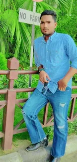 Young man posing outdoors with greenery and no parking sign.