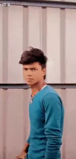 Young man posing in blue shirt with urban backdrop.