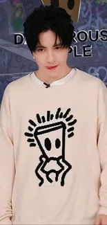 Person wearing a beige sweatshirt with graffiti design.