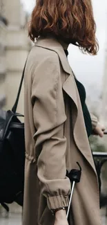 Woman wearing a beige trench coat with red hair in a city setting.