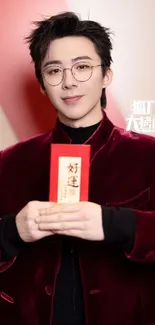 Person in velvet outfit holding red envelope with stylish backdrop.