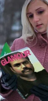 Blonde woman in pink coat reads Glamour magazine.