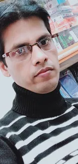 Person wearing a stylish winter striped sweater with glasses in a shop background.