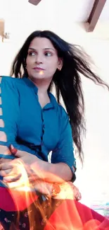 Woman in blue top with flowing hair against a neutral background.