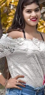 Woman in lace top and jeans with green leafy background.