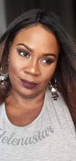 Portrait of a stylish woman with makeup and accessories in a gray top.