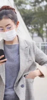 Woman in plaid coat using smartphone outside.