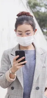 Fashionable woman with smartphone and face mask in chic attire.