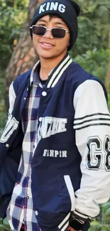 Young man in stylish outfit amidst forest backdrop, wearing sunglasses.