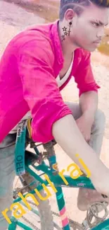 Young man in red shirt posing on a bicycle.