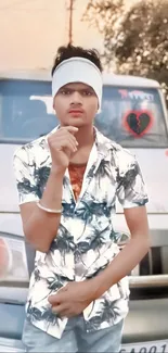 Young man confidently posing in front of a vehicle with stylish attire.